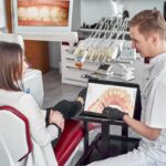 Dentysta pokazuje pacjentowi stan uzębienia
